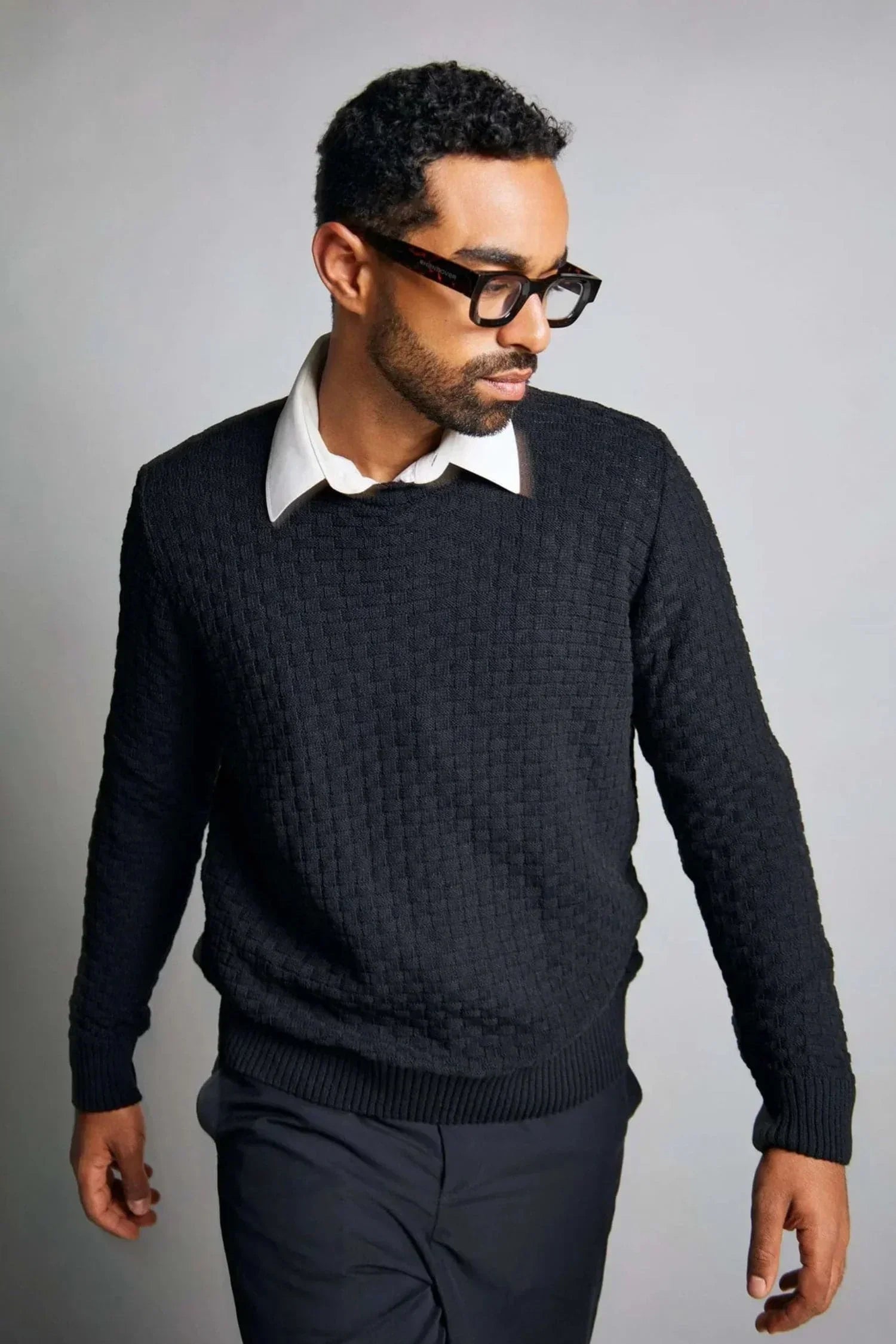 Hombre con suéter negro tejido de punto y camisa blanca, moda masculina elegante.